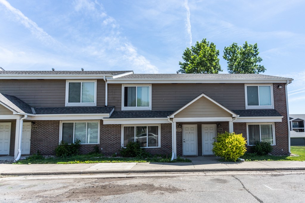 a brick house with white doors and a parking lot