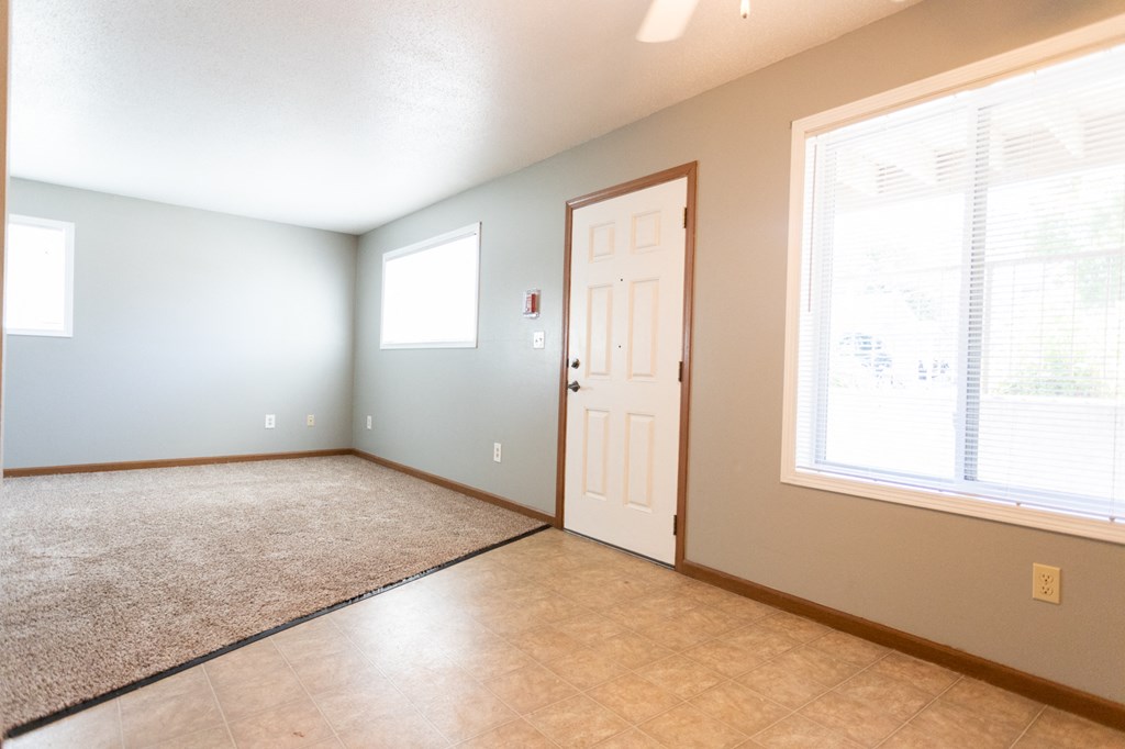 an empty living room with a white door and a window