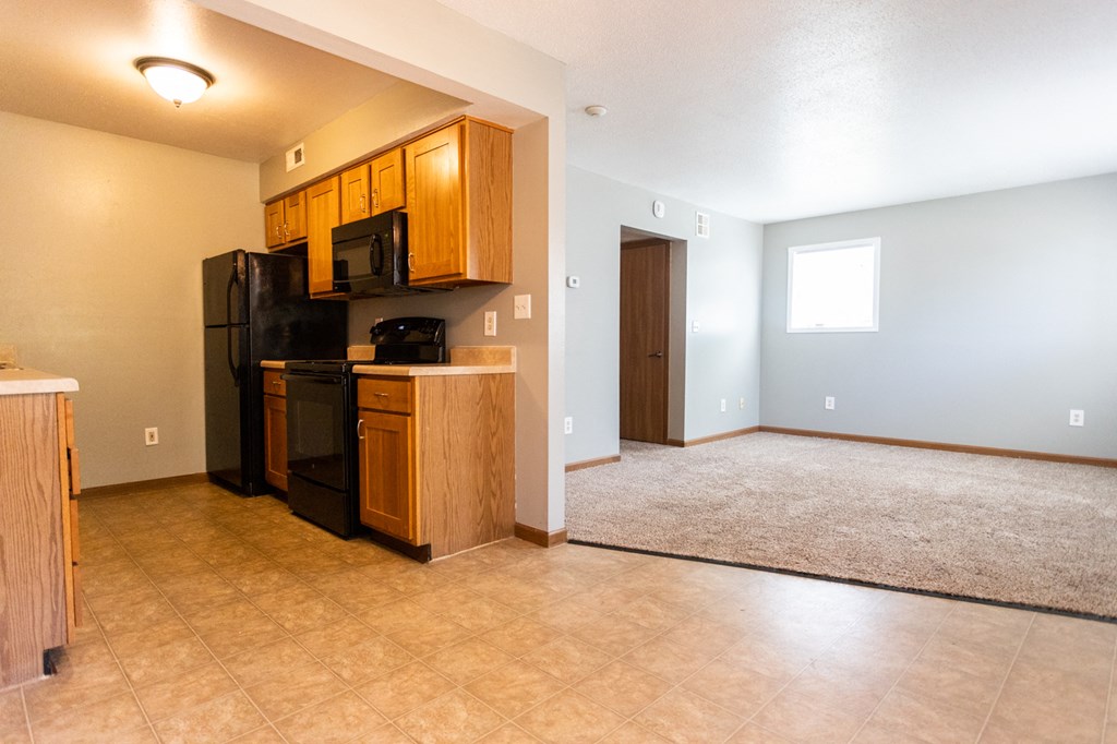 a kitchen and living room with a black refrigerator and a microwave
