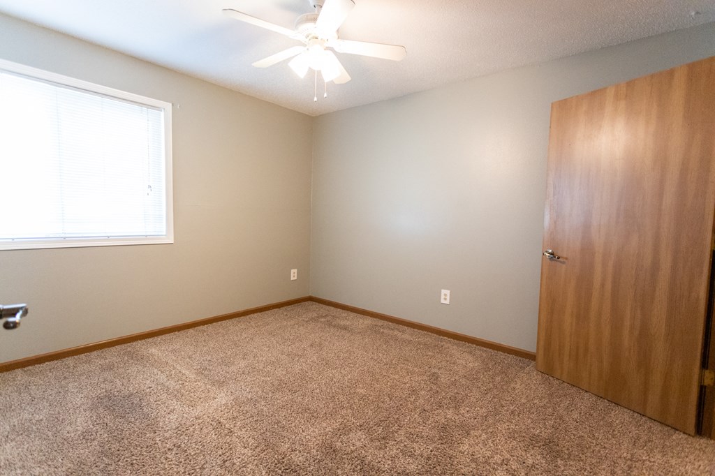 an empty bedroom with a door and a ceiling fan