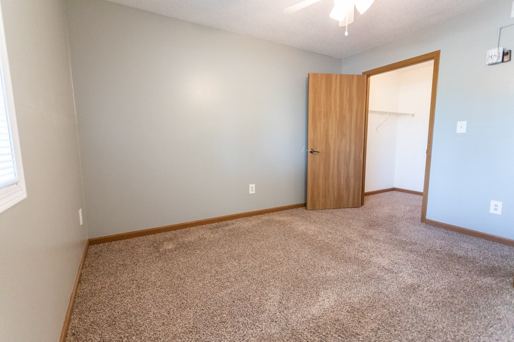 an empty room with carpet and a door to a closet
