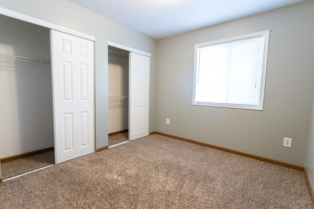 an empty bedroom with a closet and a window
