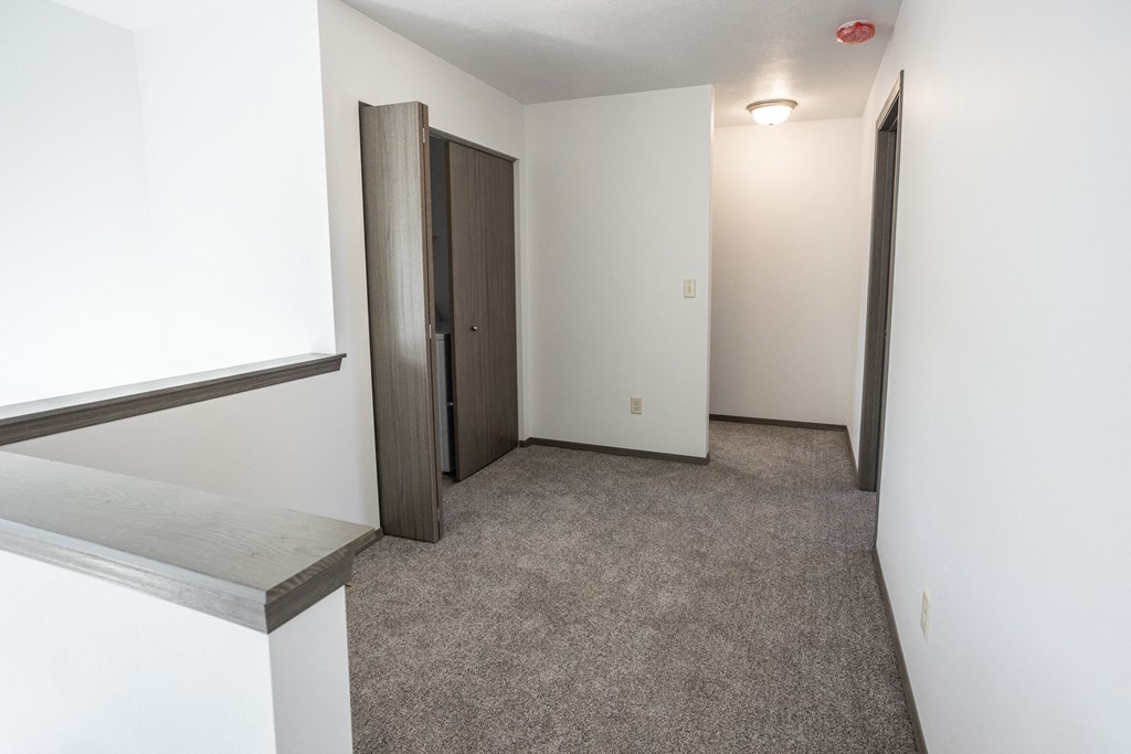an empty room with white walls and carpet and a door to a closet