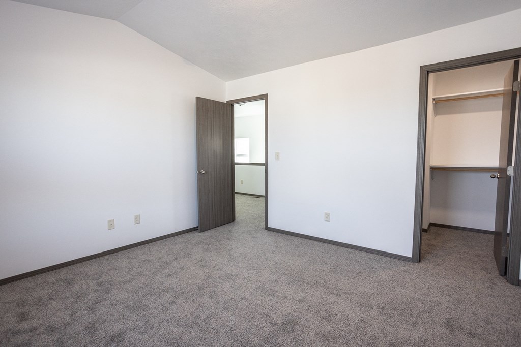 an empty bedroom with a closet and a door to a bathroom