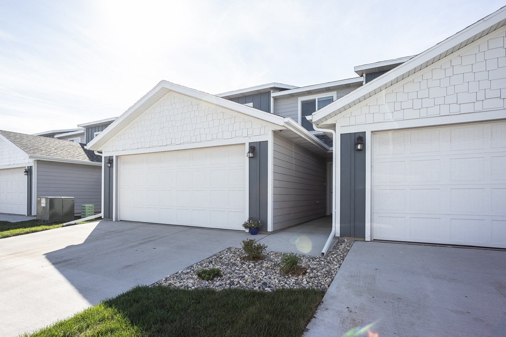 a white and gray house with two garage doors