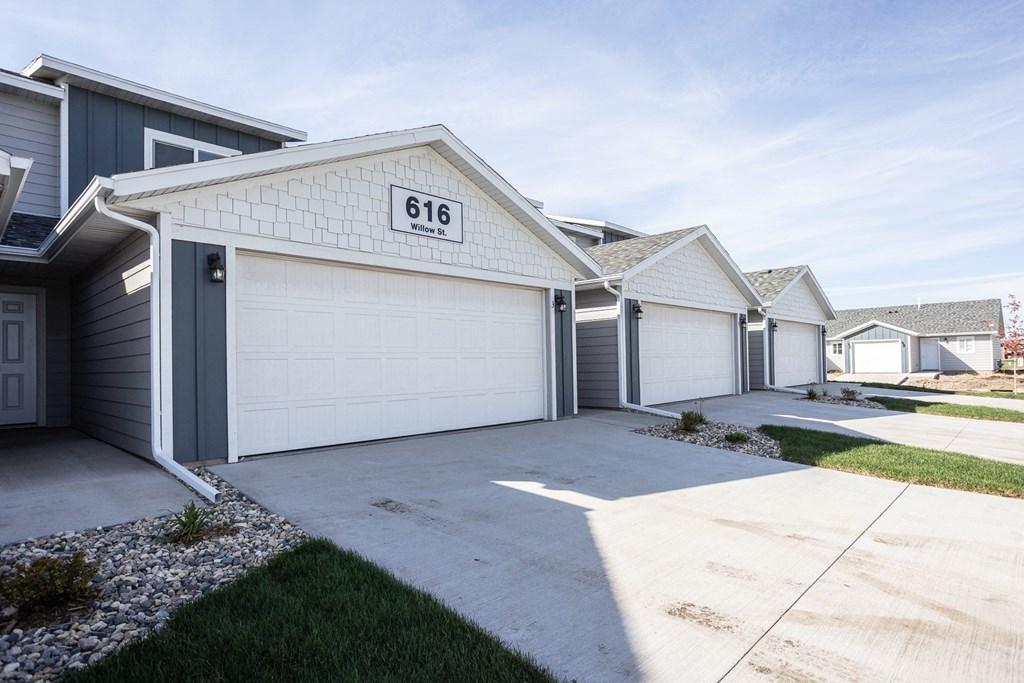 a row of houses with white garage doors and a driveway