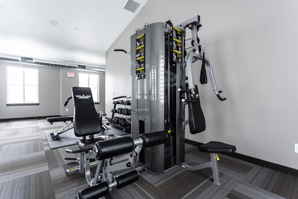 a gym with weights and cardio equipment in a room with a window