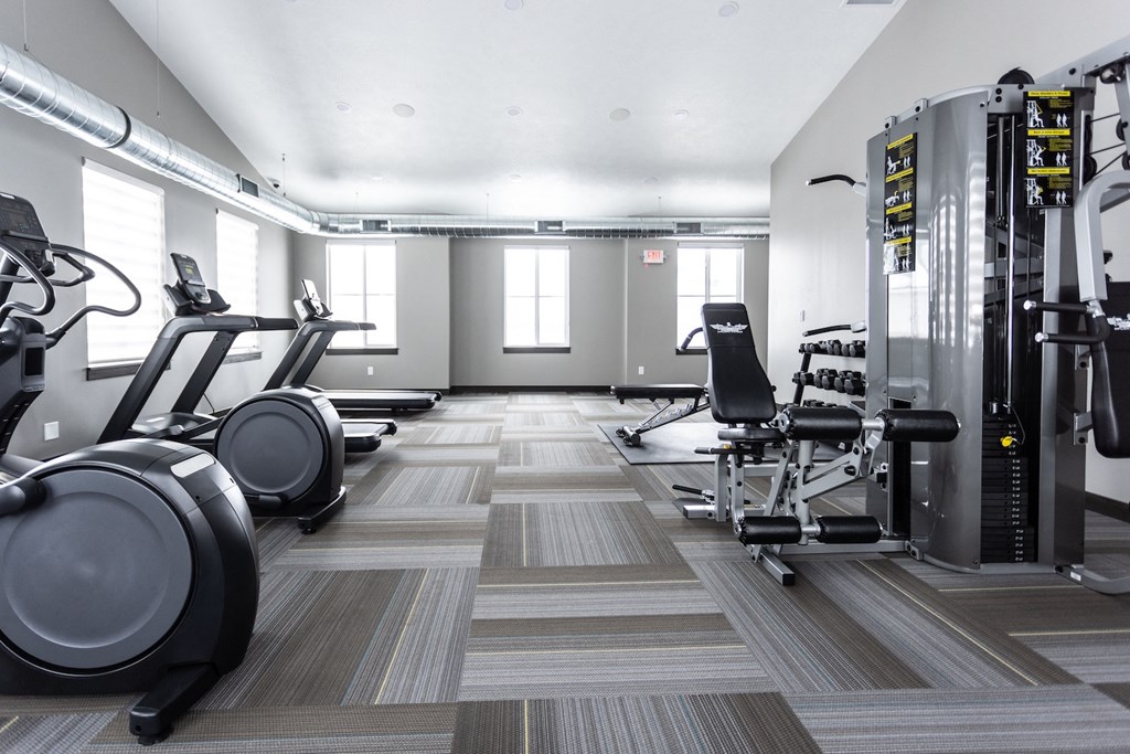 a gym with cardio machines and weights on the floor