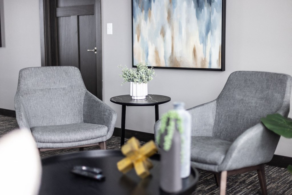 a living room with two gray chairs and a table with a vase of flowers