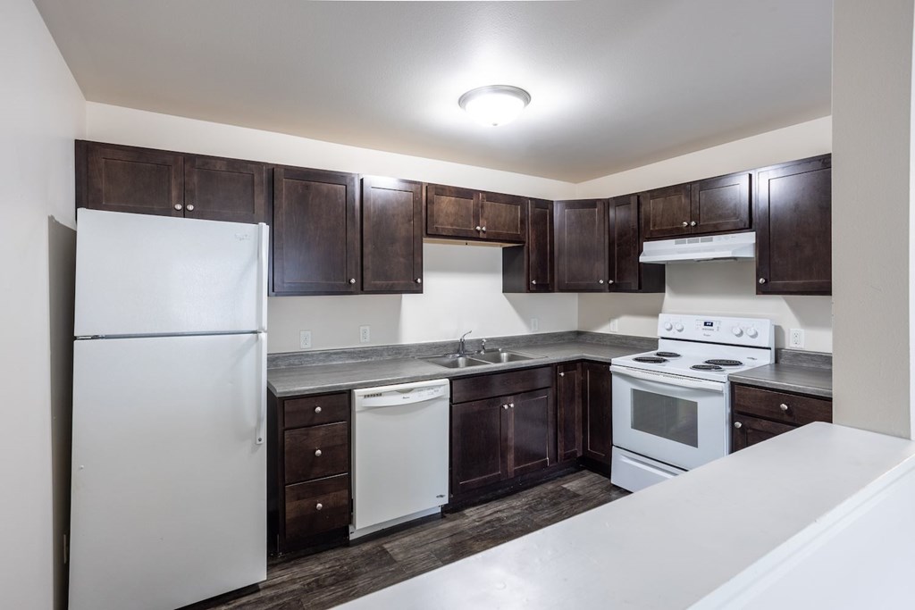a kitchen with white appliances and dark wood cabinets