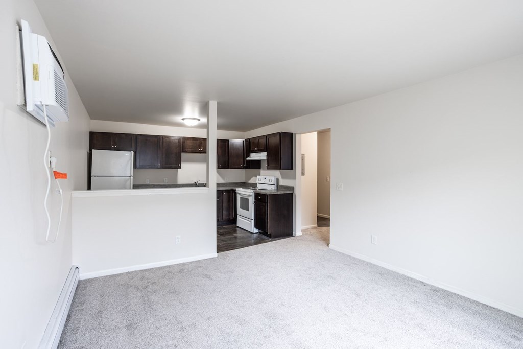 a renovated living room and kitchen with white carpet and black cabinets