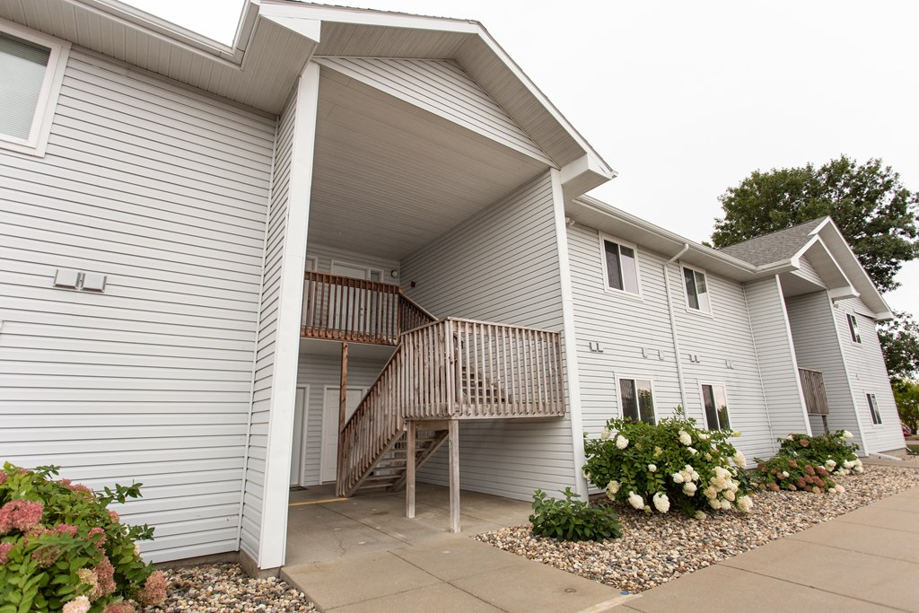 the exterior of a white house with a porch and a driveway