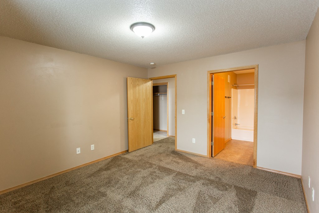 a empty living room with carpet and a door to a bathroom