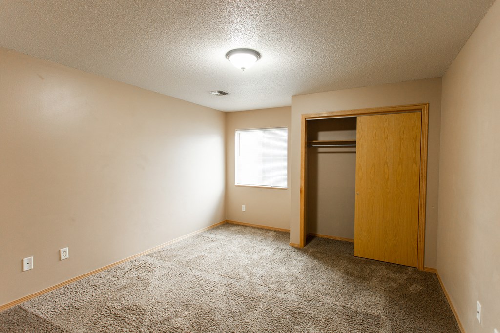 a empty room with a door to a closet and a window