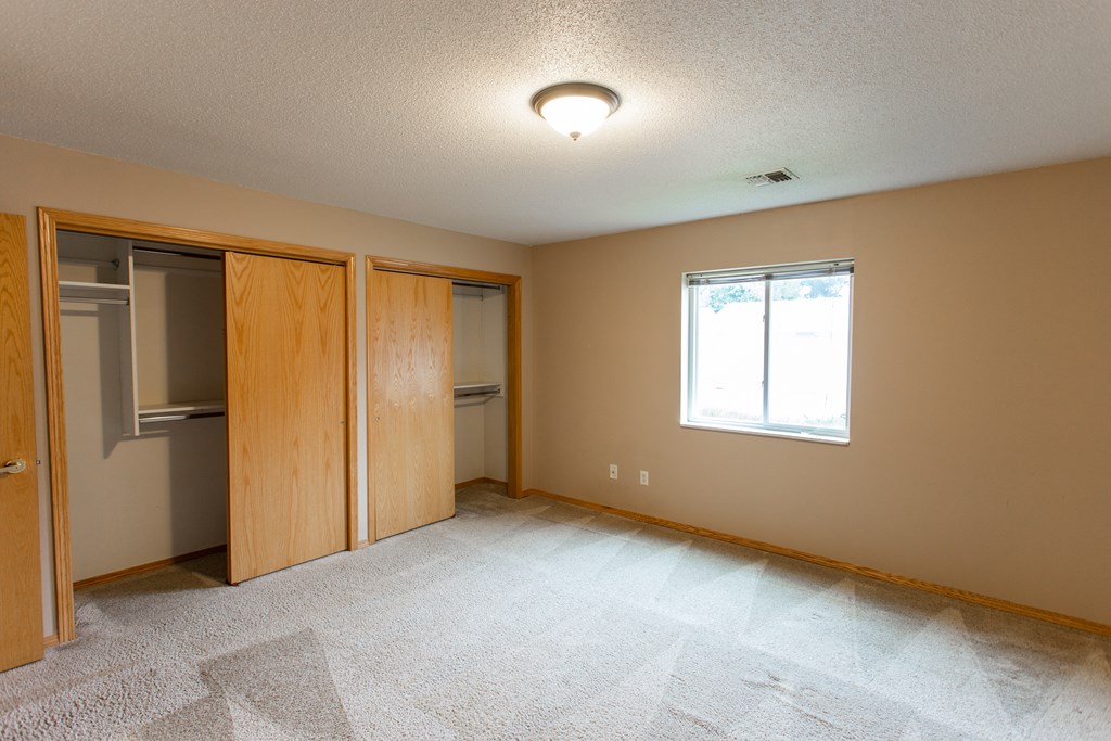 an empty bedroom with a closet and a window