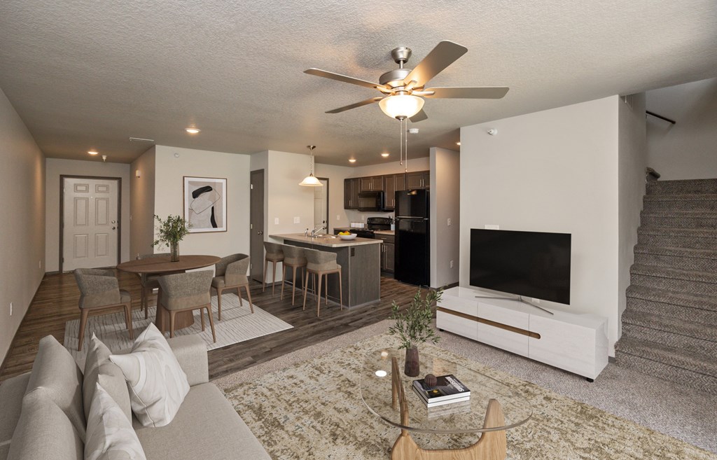 A living room with a couch, a coffee table, a television, and a staircase.