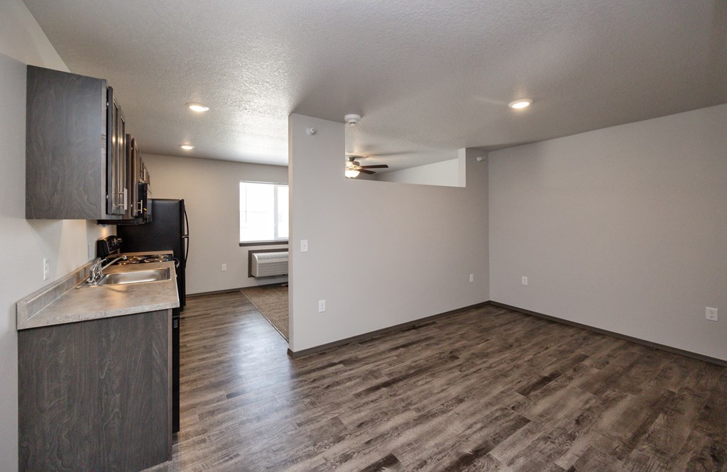 A kitchen with dark wood floors and a black refrigerator.