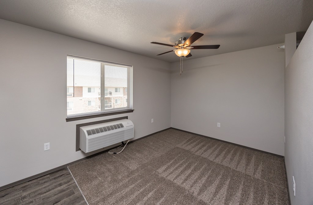 A room with a ceiling fan and carpeted floor.