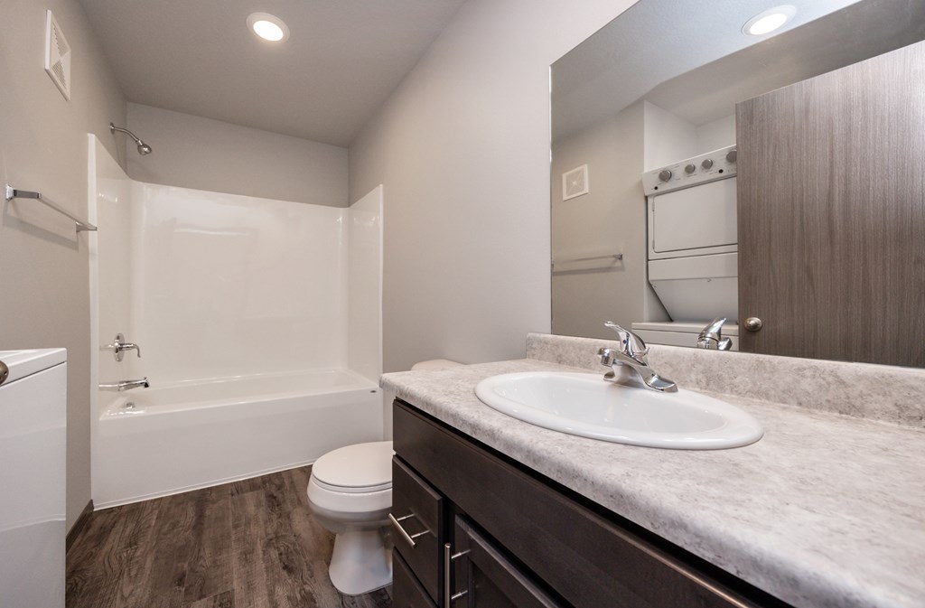 A white toilet is in a bathroom with a sink and a bathtub.