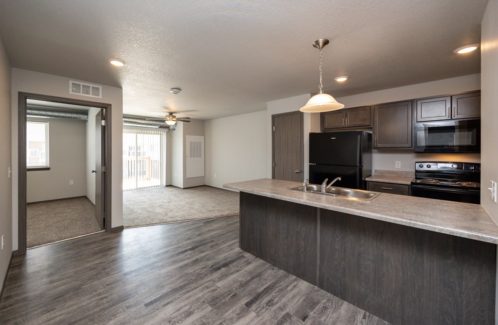 A kitchen with a black refrigerator and a sink.