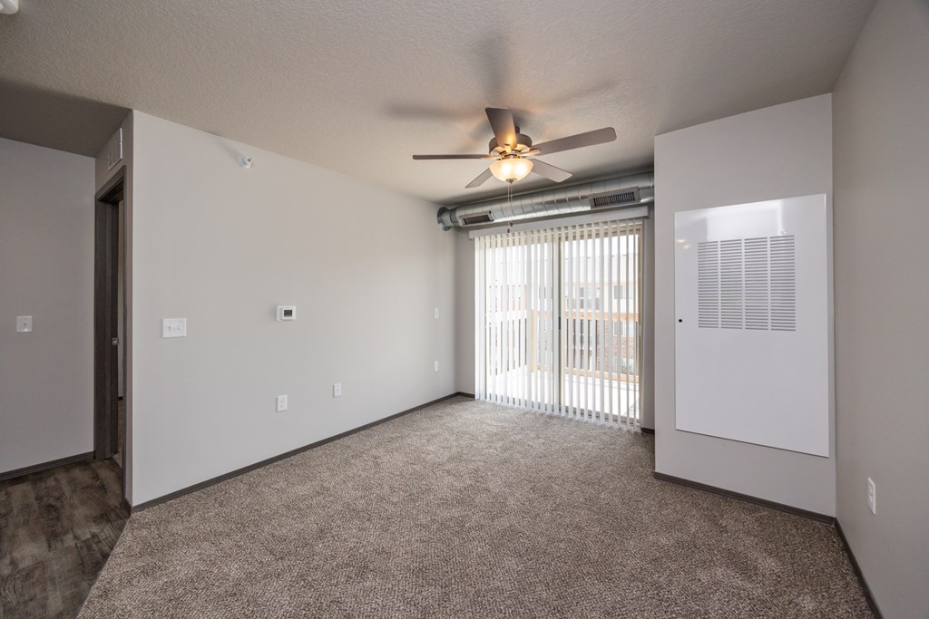 A room with a ceiling fan and a window with blinds.