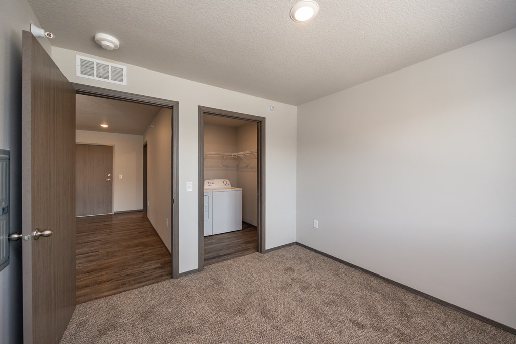A white washing machine is in a small room with a brown carpet.