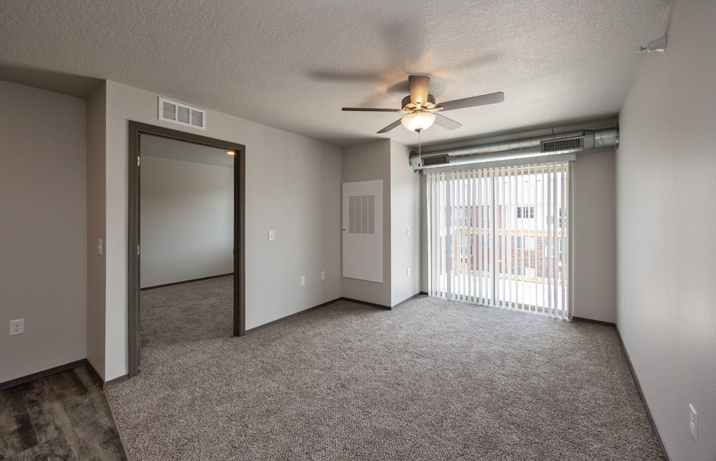 A room with a ceiling fan and sliding glass doors.