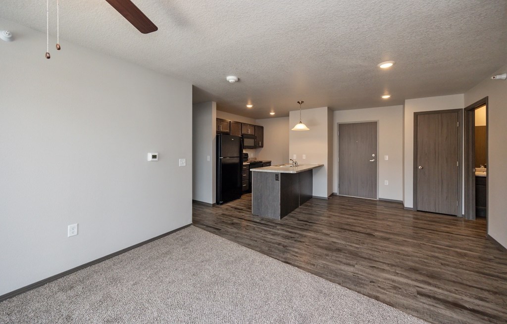 A spacious room with a kitchen area and a ceiling fan.