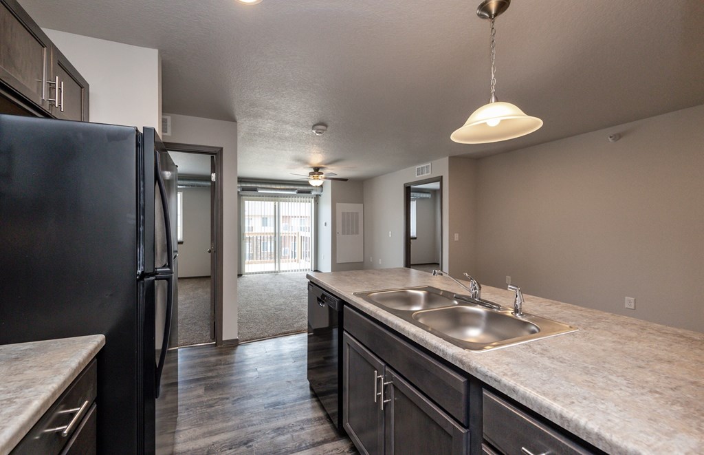 A kitchen with a black refrigerator and a marble countertop.