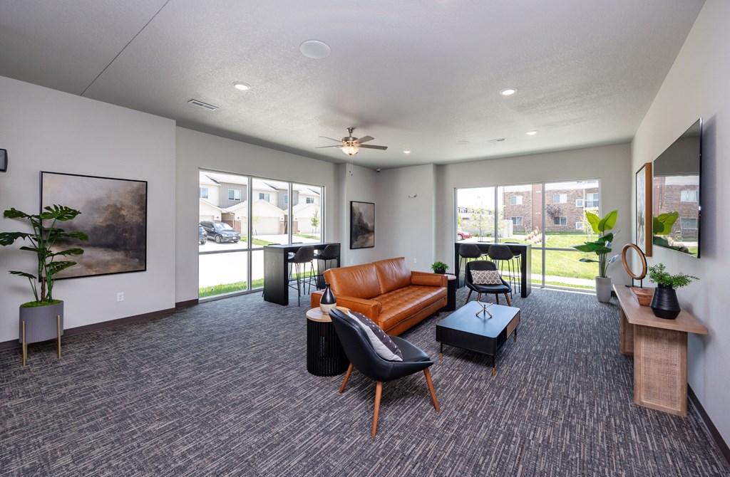 A spacious living room with grey carpeting and furniture.