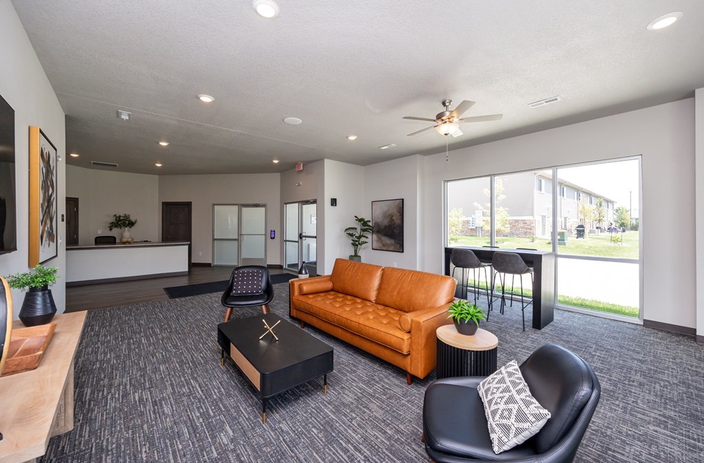 A spacious living room with a brown sofa, a black coffee table, and a ceiling fan.