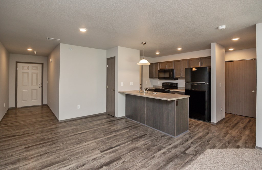 A kitchen with a black refrigerator and microwave, and a white countertop.