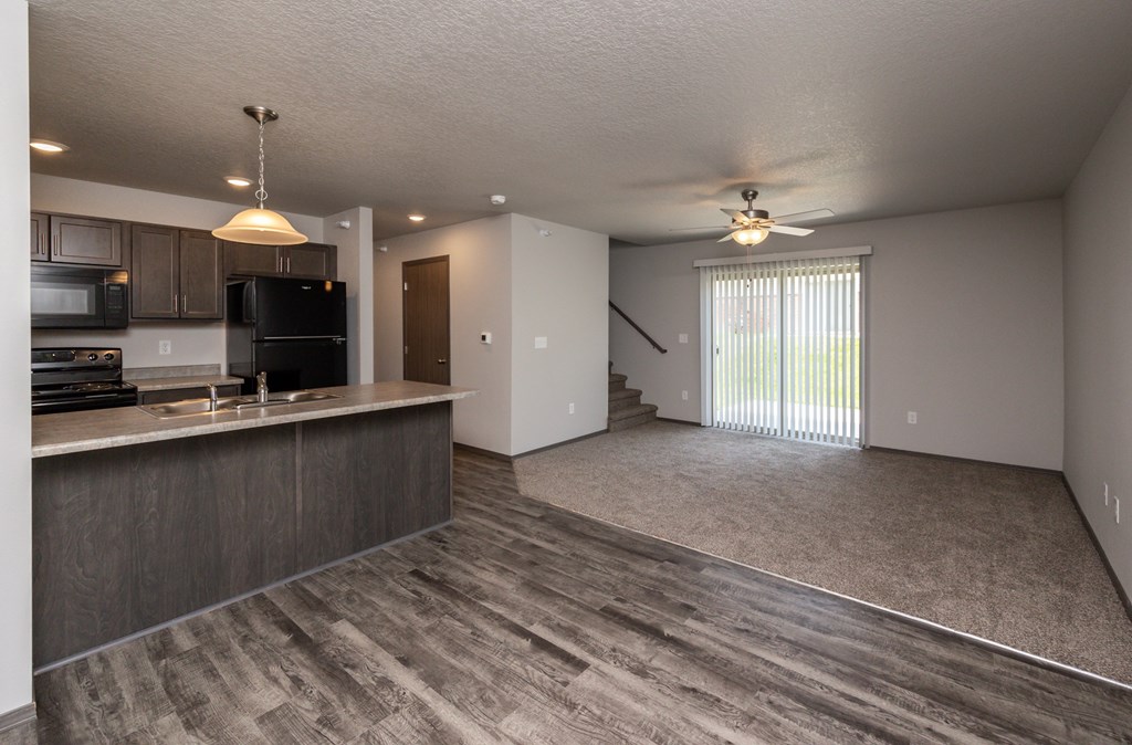 A spacious kitchen with dark wood cabinets and a black refrigerator.