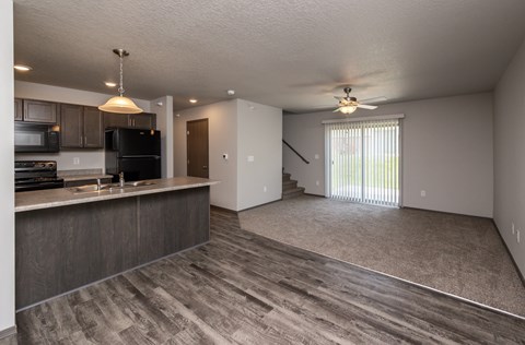 A spacious kitchen with dark wood cabinets and a black refrigerator.