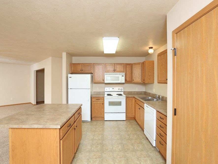 a large kitchen with white appliances and wooden cabinets