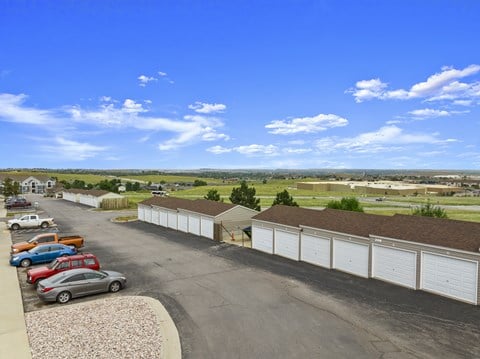 A parking lot with cars and a long row of garages.