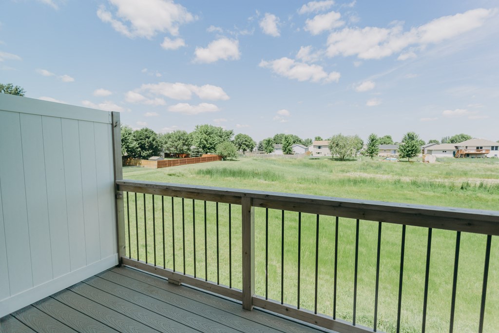 a balcony with a view of a grassy field and houses in the background