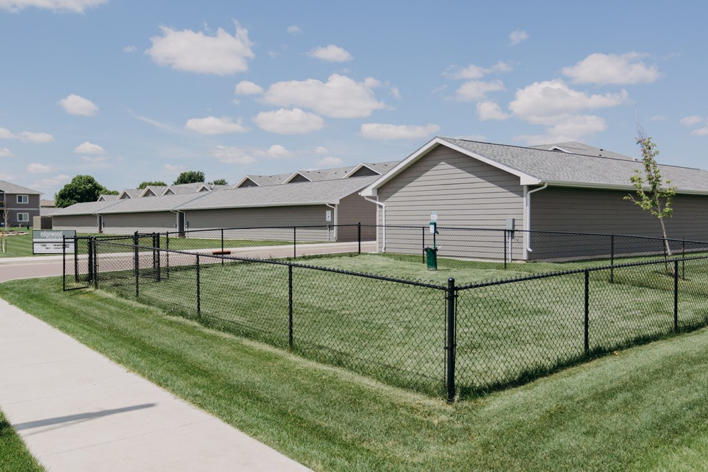 a fenced in tennis court in front of a house