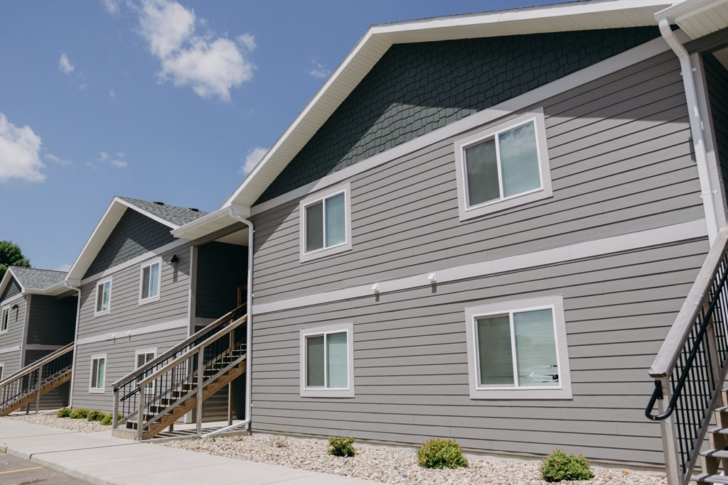 a row of houses with gray siding and a sidewalk