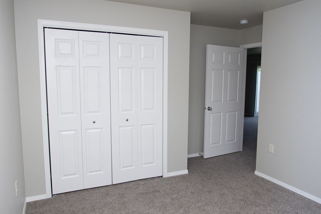 an empty bedroom with two closets and a door