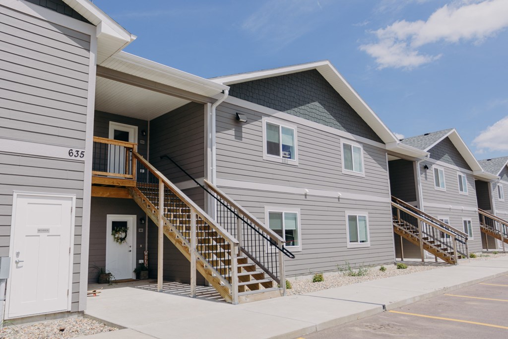 a gray building with stairs and a white door