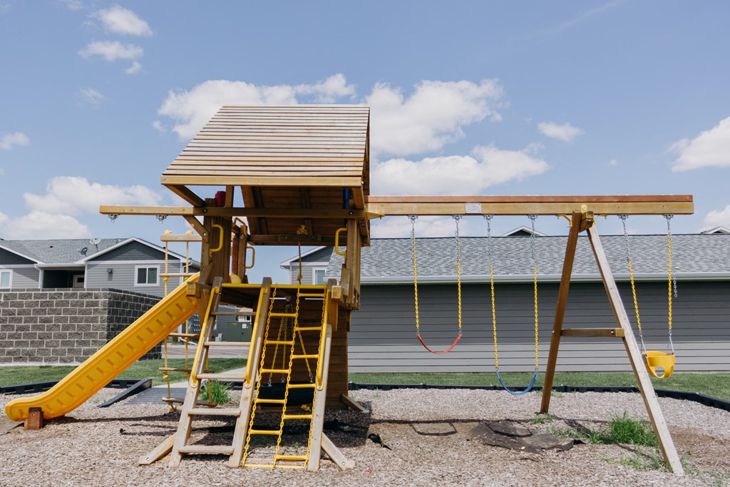 a playground with a swing set in front of a house