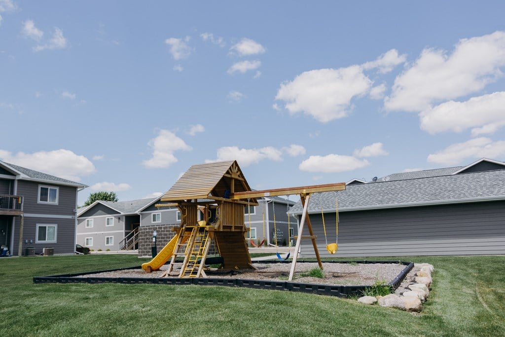 a yellow swing set in the middle of a yard