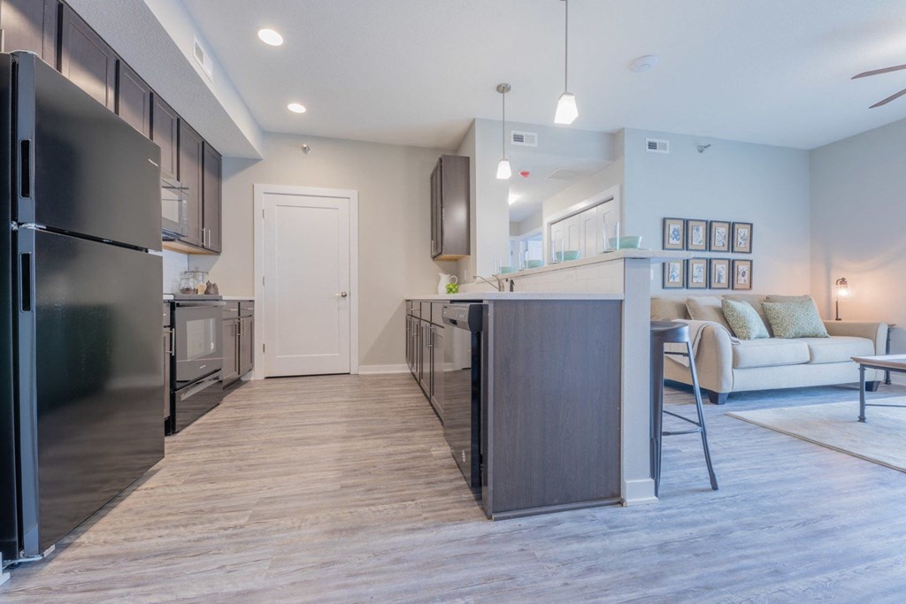 a kitchen and living room with a refrigerator and a counter top