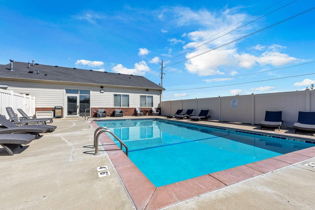 A swimming pool with a red border and lounge chairs around it.