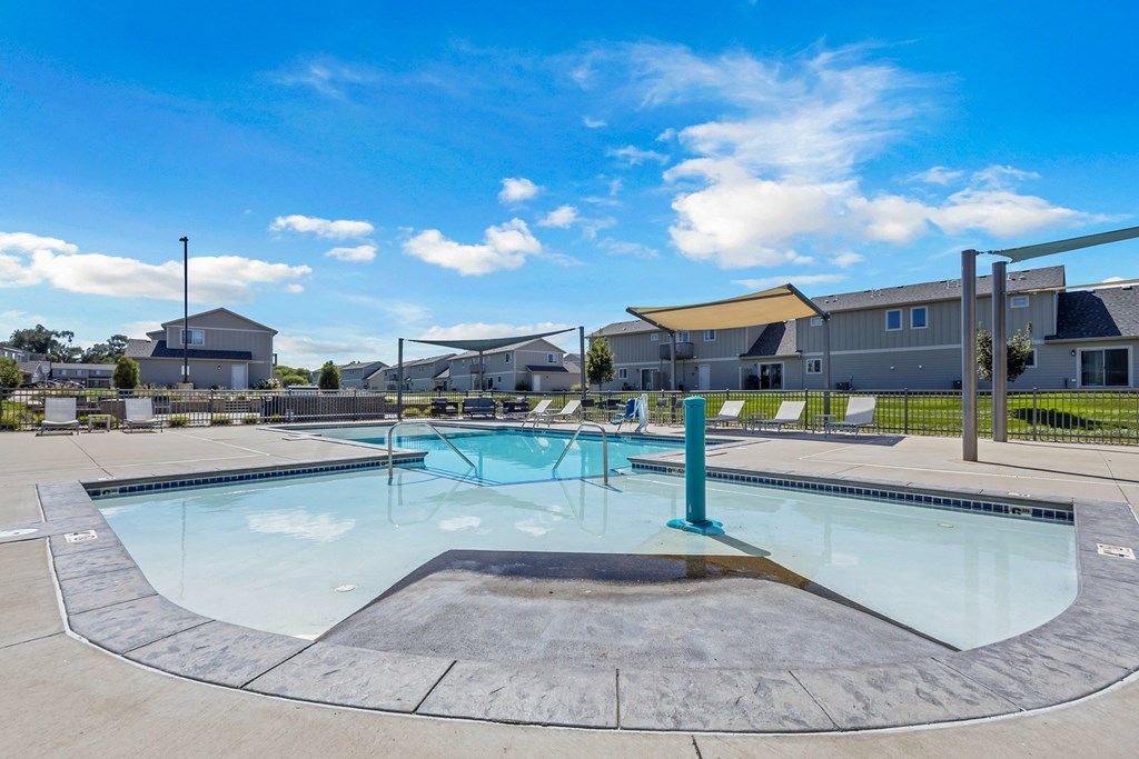 A large outdoor swimming pool with a diving board and lounge chairs.