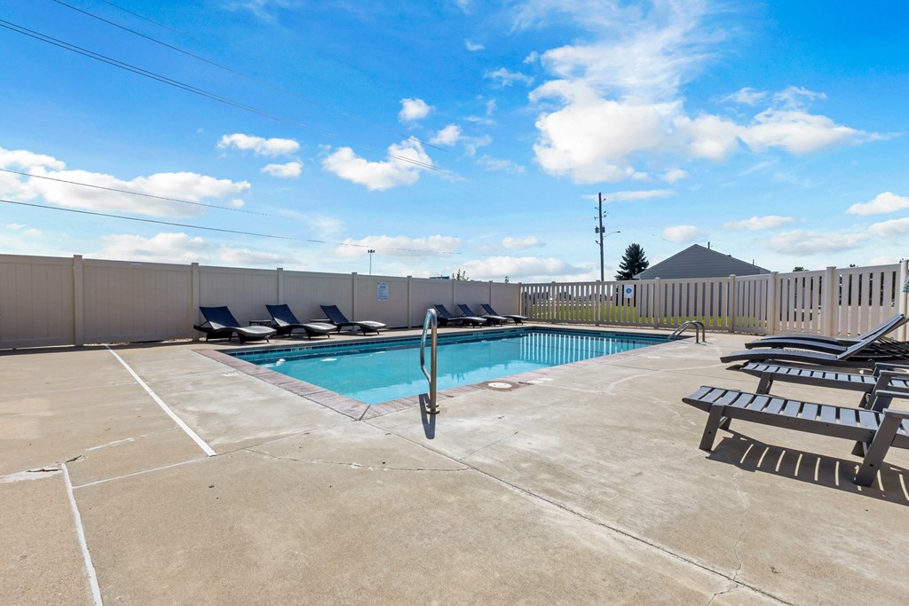 A pool with a diving board and a bench.