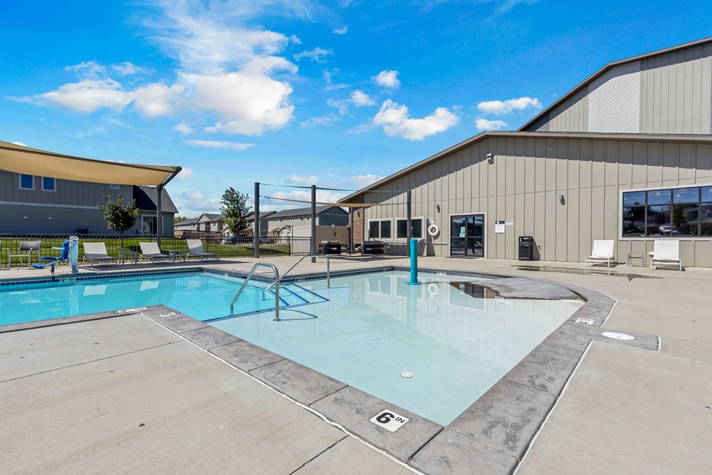A large outdoor swimming pool with a diving board and lounge chairs.