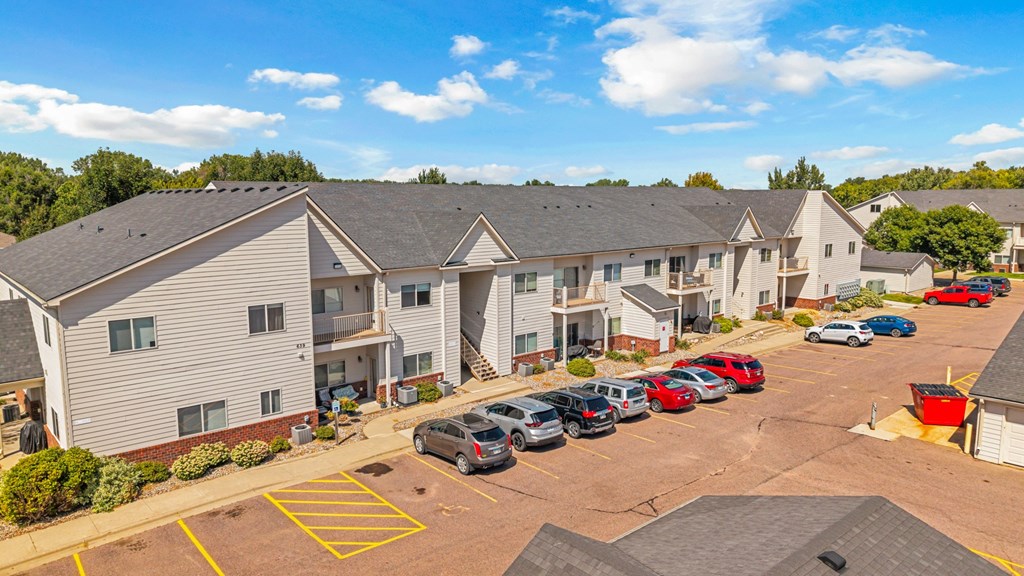 A parking lot with cars and apartment buildings in the background.
