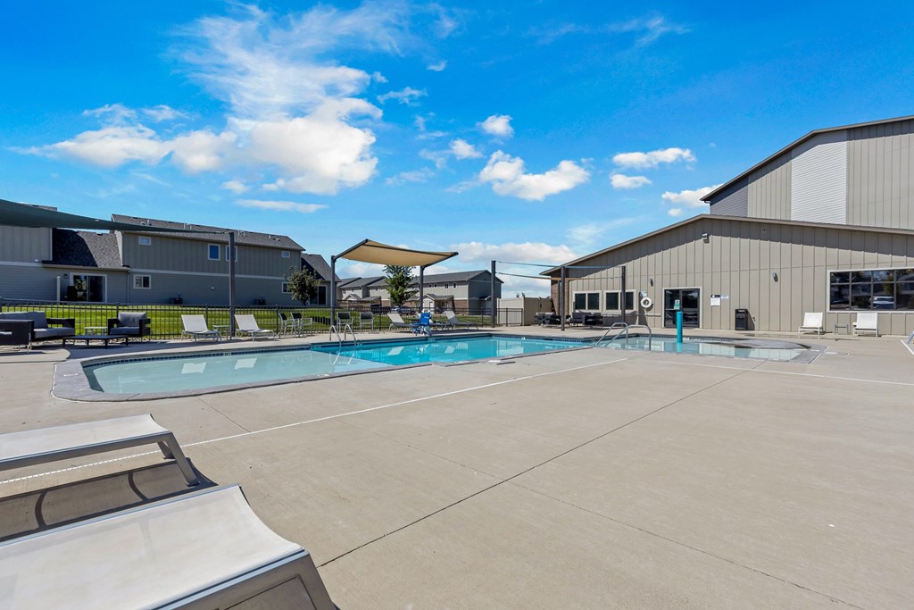 A large outdoor swimming pool with a slide and a building in the background.